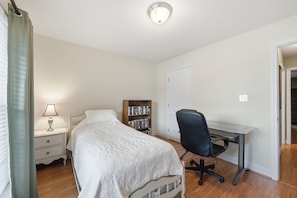 A bedroom with a bed, bedside table, lamp, bookshelf, and a desk with a chair. - Welcome to The Amsterdam Place. (Madison)