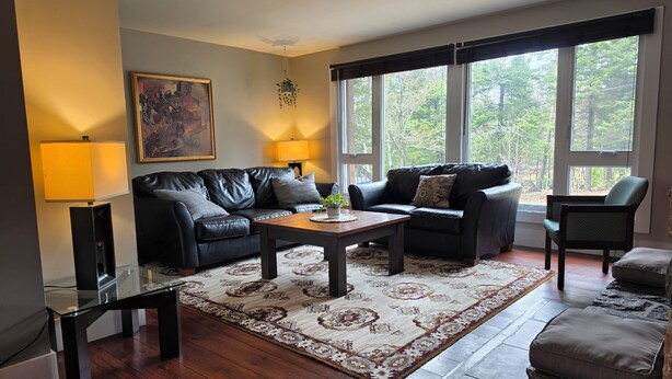 A living room with a sofa, armchairs, a coffee table, a lamp, and a painting on the wall.
