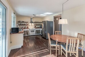 Una cocina compacta con comedor, piso de madera y horno empotrado.