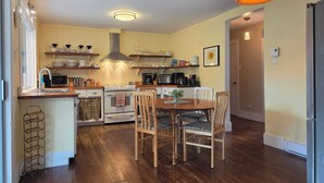 A compact kitchen with wooden cabinets, a central island, and a dining area with two chairs.