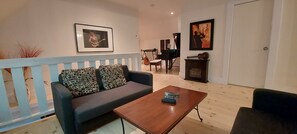 Una sala de estar con un sofá, una mesa de centro, un piano y una guitarra.