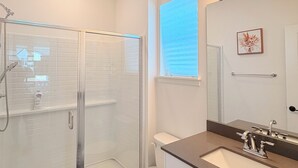 A modern bathroom with a glass-enclosed shower, a toilet, and a vanity with a mirror. - Cozy Ensuite Room Near Mt. Rainier & Seattle (Bonney Lake)
