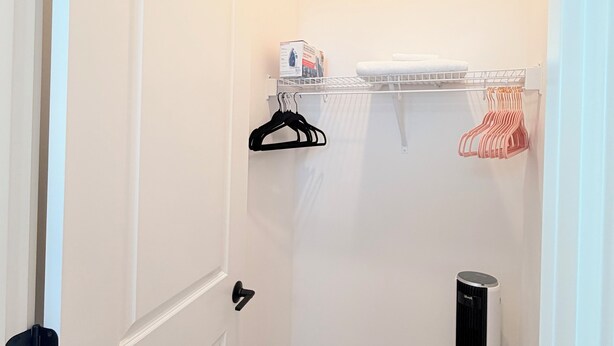 A small, well-lit room with a white door, a white radiator, a black heater, and a white towel on a shelf. - Cozy Ensuite Room Near Mt. Rainier & Seattle (Bonney Lake)