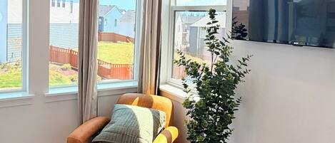 A modern living room with a sofa, a potted plant, and a television mounted on the wall.