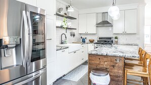 Eine moderne Küche mit Edelstahlgeräten, weißen Schränken und einer Holztheke.