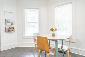 Un coin repas avec une table ronde, deux chaises et un vase de fleurs.