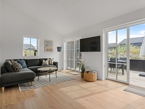 Ein modernes Wohnzimmer mit einem grauen Sofa, einem kleinen runden Tisch und einem an der Wand befestigten Fernseher.
