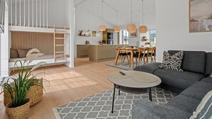 Un soggiorno moderno con camera soppalcata, zona pranzo e cucina.