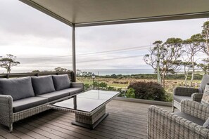 Ein Balkon mit einer Couch, einem Couchtisch und Korbstühlen.