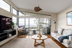 Ein modernes Wohnzimmer mit großem Fenster, einem runden Couchtisch und einer Couch.