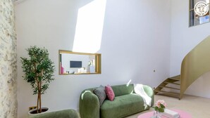 Uma sala de estar moderna com um sofá verde, uma mesa rosa e uma planta em vaso.