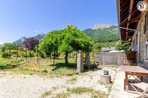 Un espace extérieur rustique agrémenté d’une pergola, d’une table en pierre et d’une clôture en bois.