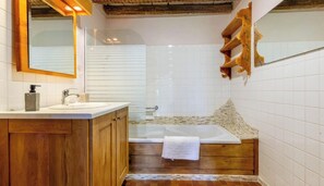 Une salle de bain avec un meuble-lavabo en bois, une cabine de douche en verre et une baignoire.