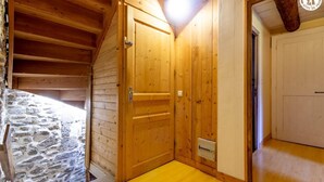 A wooden room with a stone wall, a wooden door, and a wooden ceiling. - The Priory Gardens (CLERY)