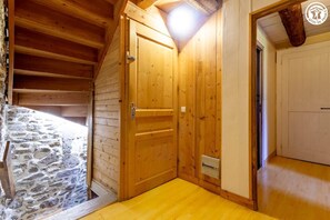 Ein Zimmer mit Holzboden, einer Steinsäule, einer Holztür und einer Holzzielde.