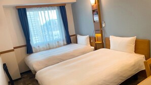 A hotel room with two beds, a window with curtains, a bedside table, and a lamp. - Toyoko Inn Mito Eki Minami Guchi (Mito)