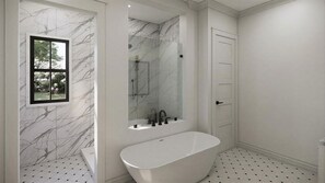Ein Badezimmer mit freistehender Badewanne, einem Fenster mit Blick auf Bäume und einer Tür.
