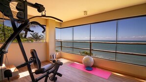 A gym with exercise equipment and a large window overlooking the ocean. - Kilombo Villas And Spa (Tibau do Sul)