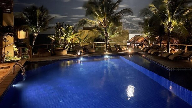A nighttime pool area with palm trees, lounge chairs, and a clear sky. - Kilombo Villas And Spa (Tibau do Sul)