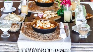 A dining table set with various dishes, drinks, and a decorative wall with hats. - Kilombo Villas And Spa (Tibau do Sul)