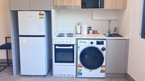 A compact kitchen with a refrigerator, microwave, stove, oven, and washing machine. - Private studio near street (Padstow)