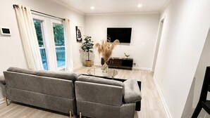 Ein modernes Wohnzimmer mit einem grauen Ecksofa, einem flachbildfernseher an der Wand und Holzböden.