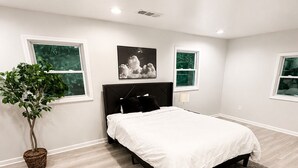 Ein Schlafzimmer mit einem Bett, einer Topfpflanze und einem grauen Teppich.