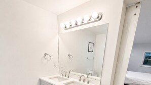 Ein modernes Badezimmer mit einem Doppelwaschtisch, einem großen Spiegel und einer beleuchteten Ablagefläche.