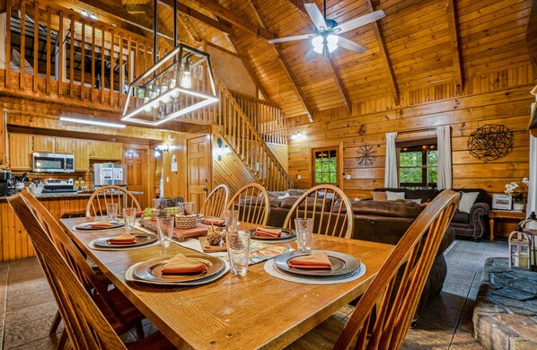 Interior de una cabaña de madera con comedor, cocina y sala de estar.