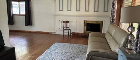 A living room with a sofa, a fireplace, a television, and a patterned rug.