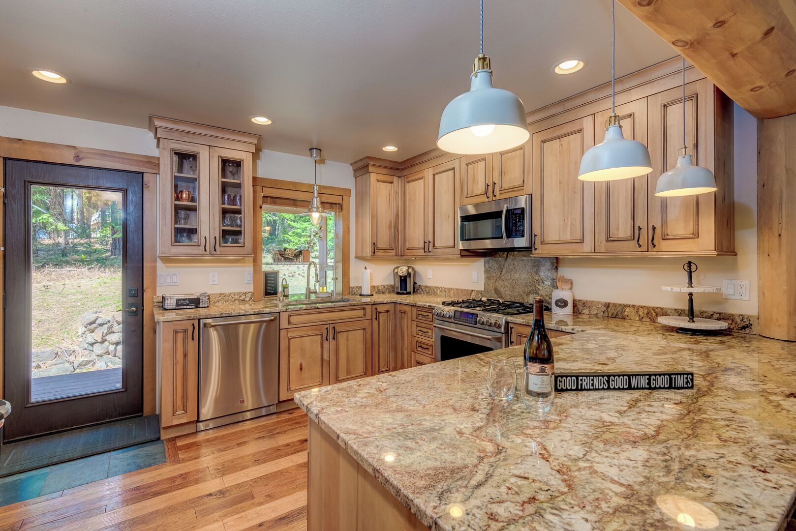 A kitchen with wooden cabinets, a granite countertop, stainless steel appliances, and pendant lighting.