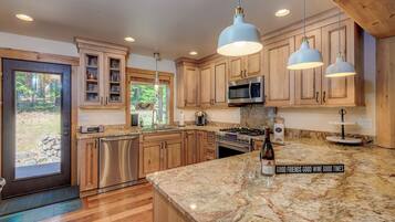 A kitchen with wooden cabinets, a granite countertop, stainless steel appliances, and pendant lighting.