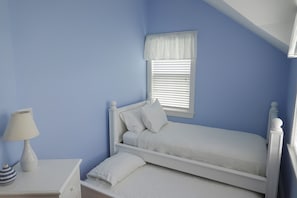 A bedroom with a single bed, a nightstand with a lamp, and a window with blinds. - Charming 4-bedroom house in Miacomet (Nantucket)