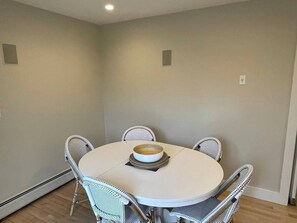 Une table de salle à manger ronde, avec quatre chaises, un saladier et une assiette posés sur la table.