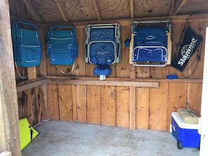 Une pièce aux murs en bois, au sol en béton et avec une glacière bleue sur laquelle est posé un sac.