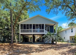 A two-story house with a balcony, surrounded by trees. - Family & Dog Friendly Retreat w. Beach, Dog, and Baby Gear. Screened porch! (Oak Island)
