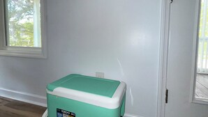 Una stanza con un frigorifero verde acqua e bianco, un cartello a parete con la scritta 'Relax' e una finestra.