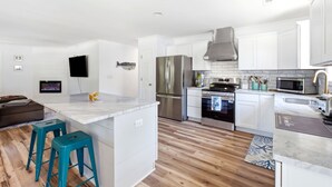 Una cucina moderna con mobili bianchi, elettrodomestici in acciaio inossidabile e un'isola in marmo.