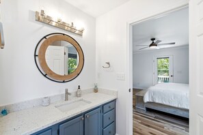 Une salle de bain avec un miroir rond, un lavabo et un meuble-vasque avec des placards.