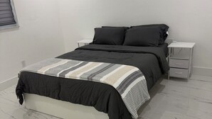 A bedroom with a bed, a nightstand, and a drawer unit. - Modern unit with premium finish, porcelain floor and rain fall shower (Hollywood)