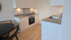 Une cuisine moderne avec des meubles blancs, un four encastré et un évier.