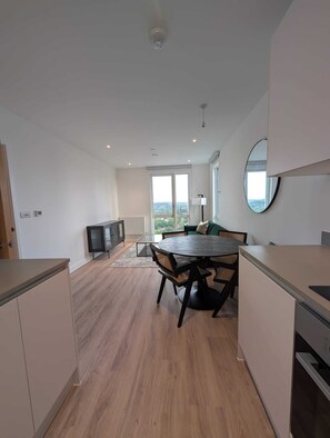 A modern kitchen with a dining area, large windows, and a view of the outdoors. - Stylish 1 bed Apt - 16 mins to central London (Croydon)