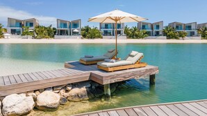 A resort with a wooden deck, lounge chairs, and a pool. - Oceanfront Villa | Balcony | Designer 3BR with Endless Views (Long Bay Hills)
