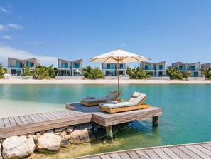 A resort with a wooden deck, lounge chairs, and a pool. - Oceanfront Villa | Balcony | Designer 3BR with Endless Views (Long Bay Hills)