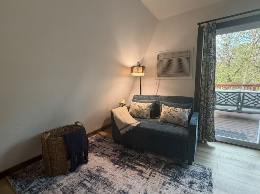 A room with a bed, a lamp, a window with a view, and a balcony.
