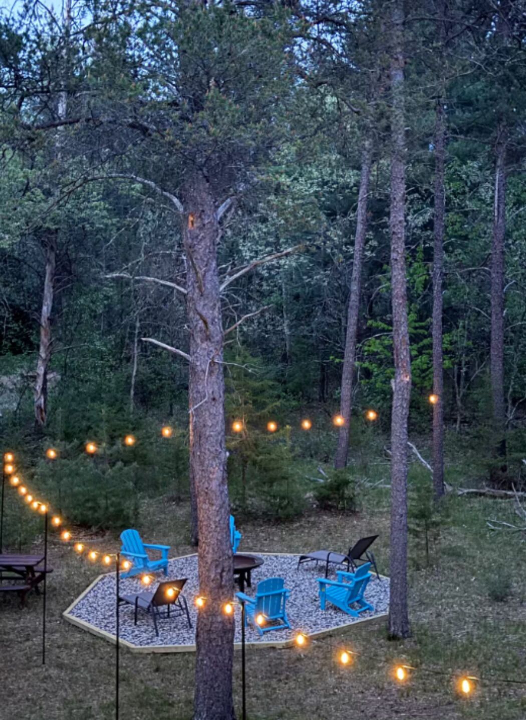 An outdoor seating area with chairs and tables, surrounded by trees.