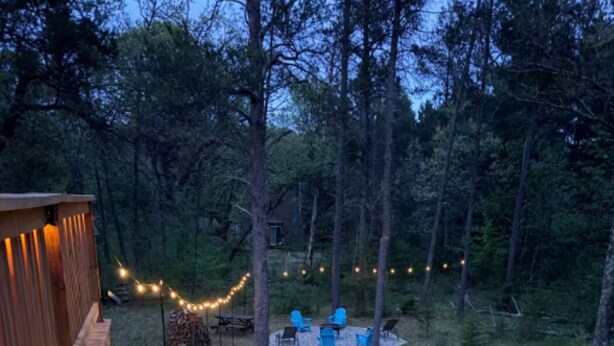 A wooden deck with a stone pathway leading to a seating area surrounded by trees.