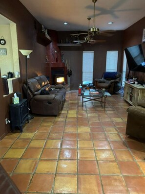 Ein Wohnzimmer mit Ecksofa, Couchtisch, Kamin und Deckenventilator.