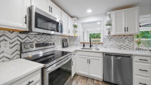 A modern kitchen with white cabinetry, a stainless steel range, and a dishwasher. - Coastal Retreat w/ Putting Green & Private Backyard. Minutes to Beach & Downtown (Venice)