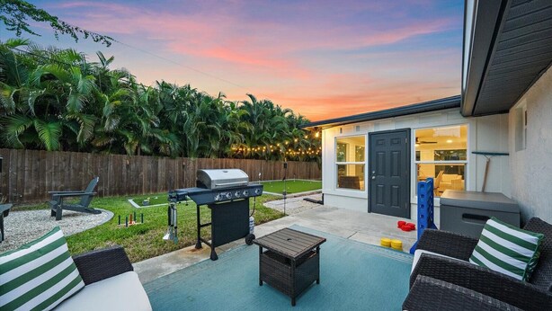 A backyard with a grill, outdoor seating, a small house, and a wooden fence. - Coastal Retreat w/ Putting Green & Private Backyard. Minutes to Beach & Downtown (Venice)